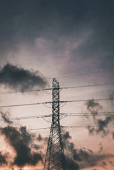 Indra Malike - A high voltage electrical tower silhouette set against a moody and colorful evening sky in Tanete Rilau, South Sulawesi.